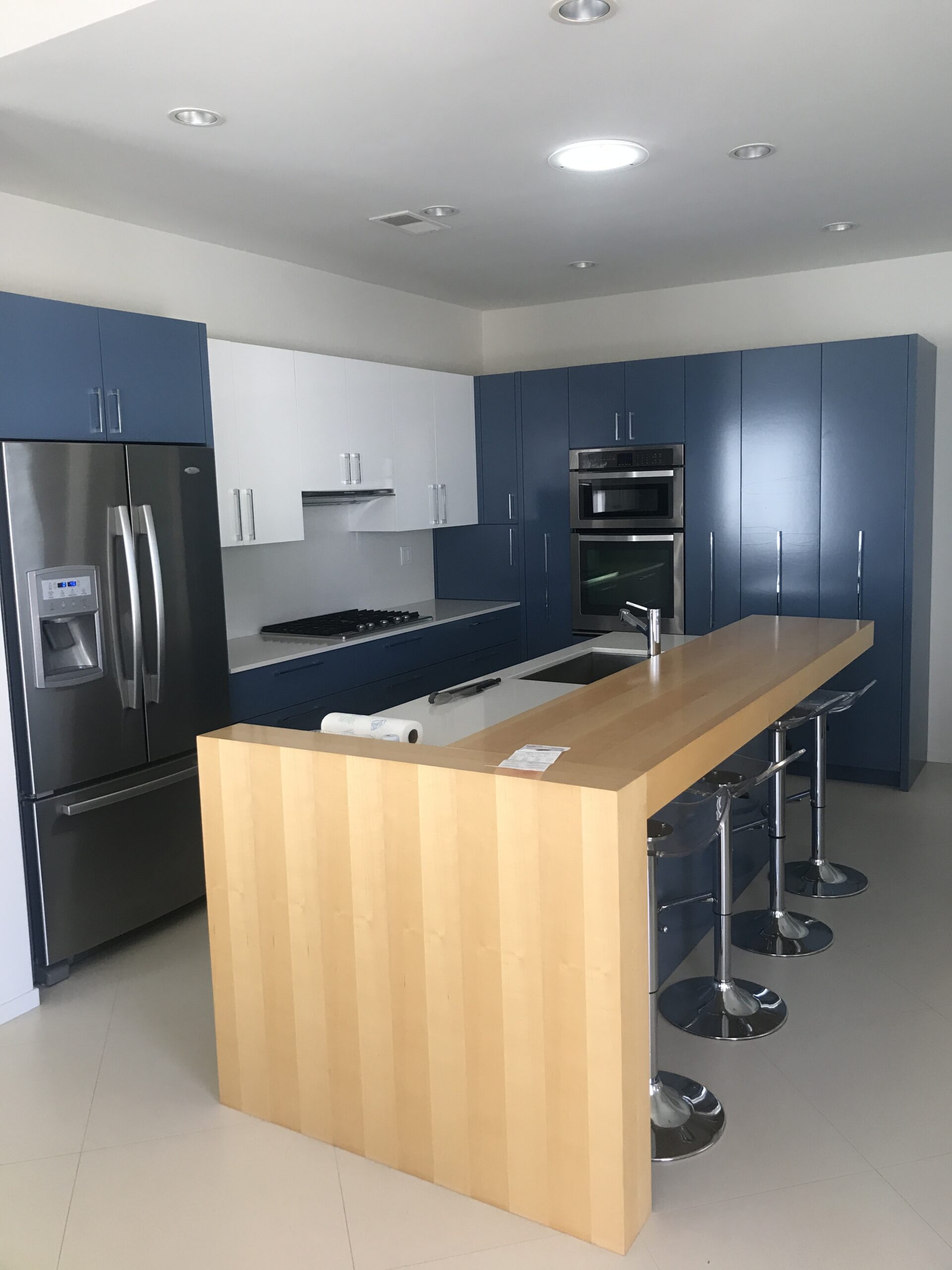 A picture of a kitchen with slightly dark blue appliances and a wooden table