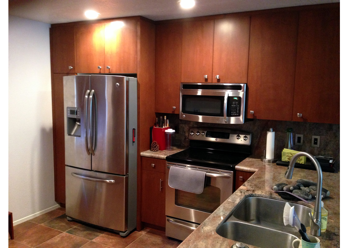 A view of some cabinets, a refrigerator, a microwave, and an oven. A sink is partially visible.