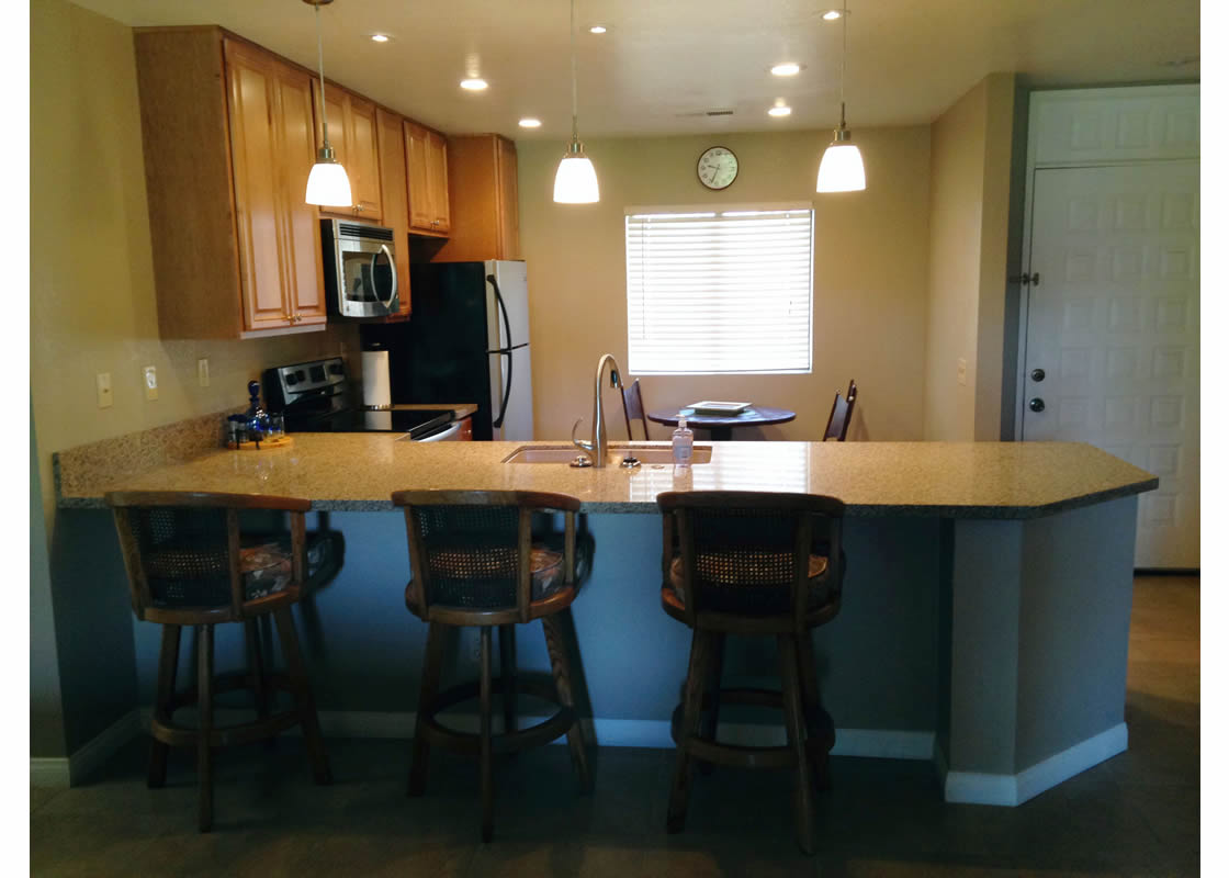 A picture of a countertop, with chairs and stylish lighting.