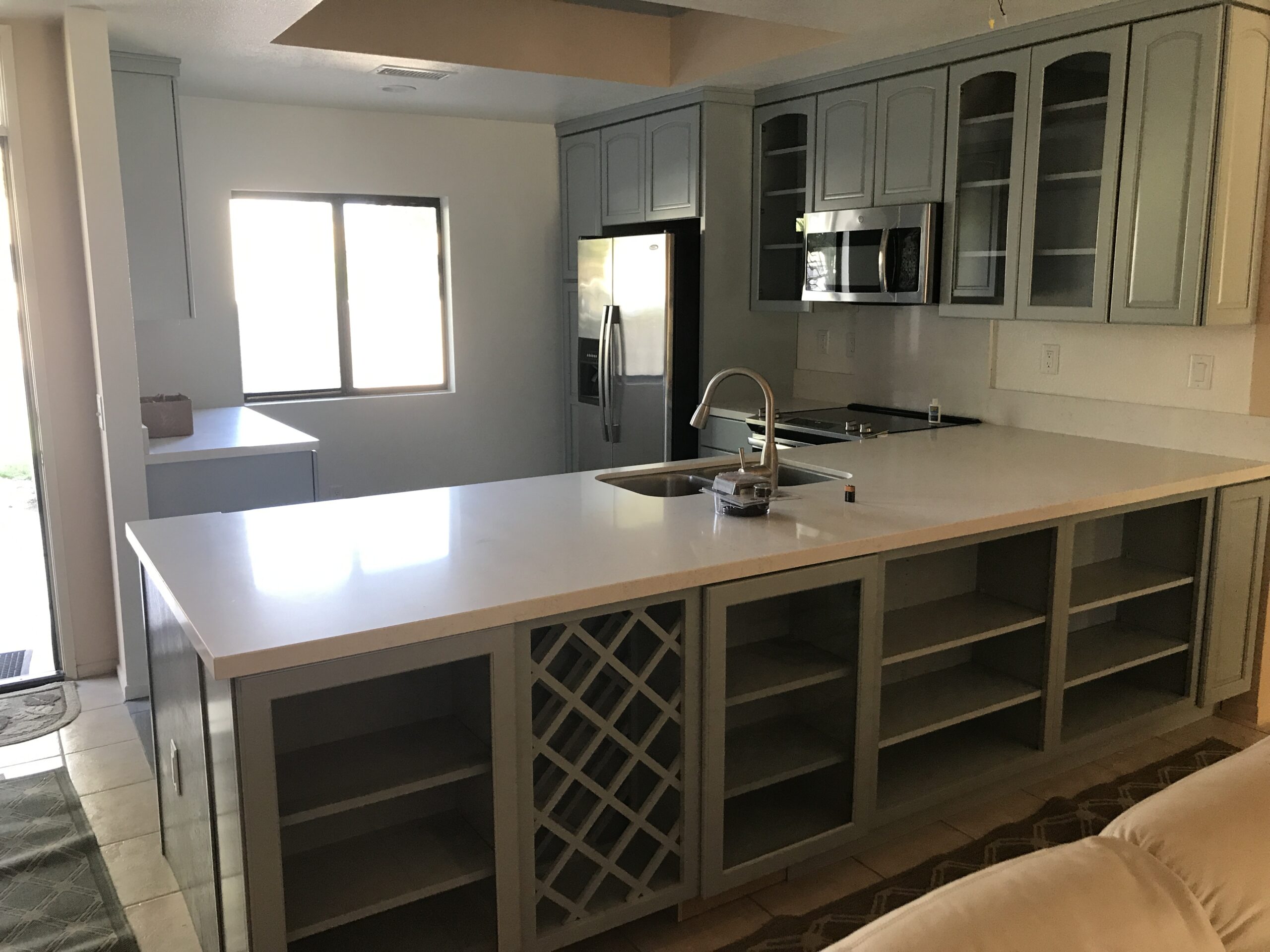 A wide picture of a kitchen, with a sink in the center.